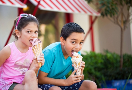 Two kids outside eating ice cream.