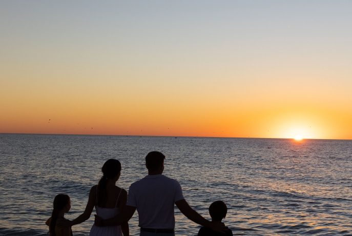 Family of 4 looking out at beach sunset