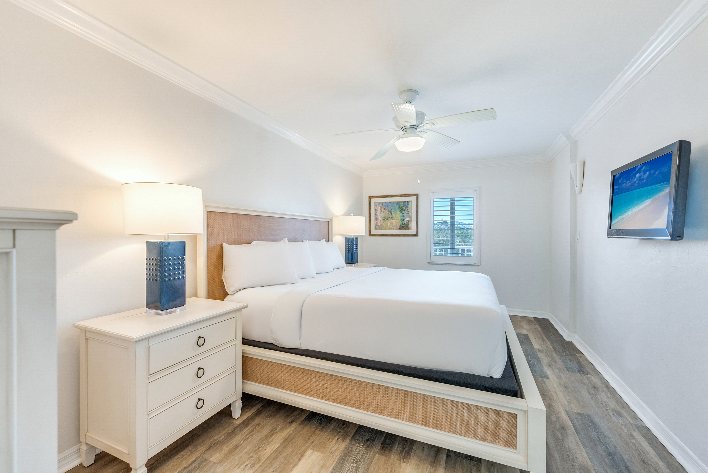 Bedroom with king bed, white walls, and blue lamps.