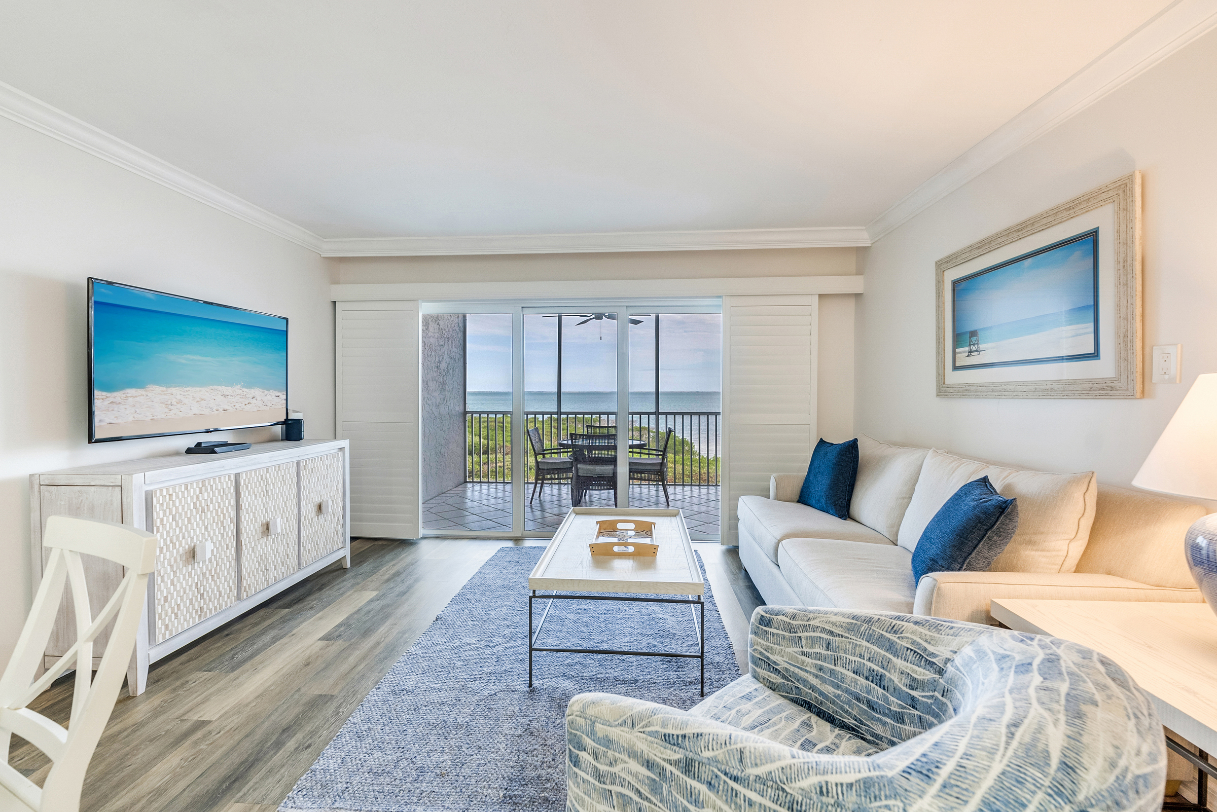 Bright living room with ocean view, blue accents, and sliding glass doors
