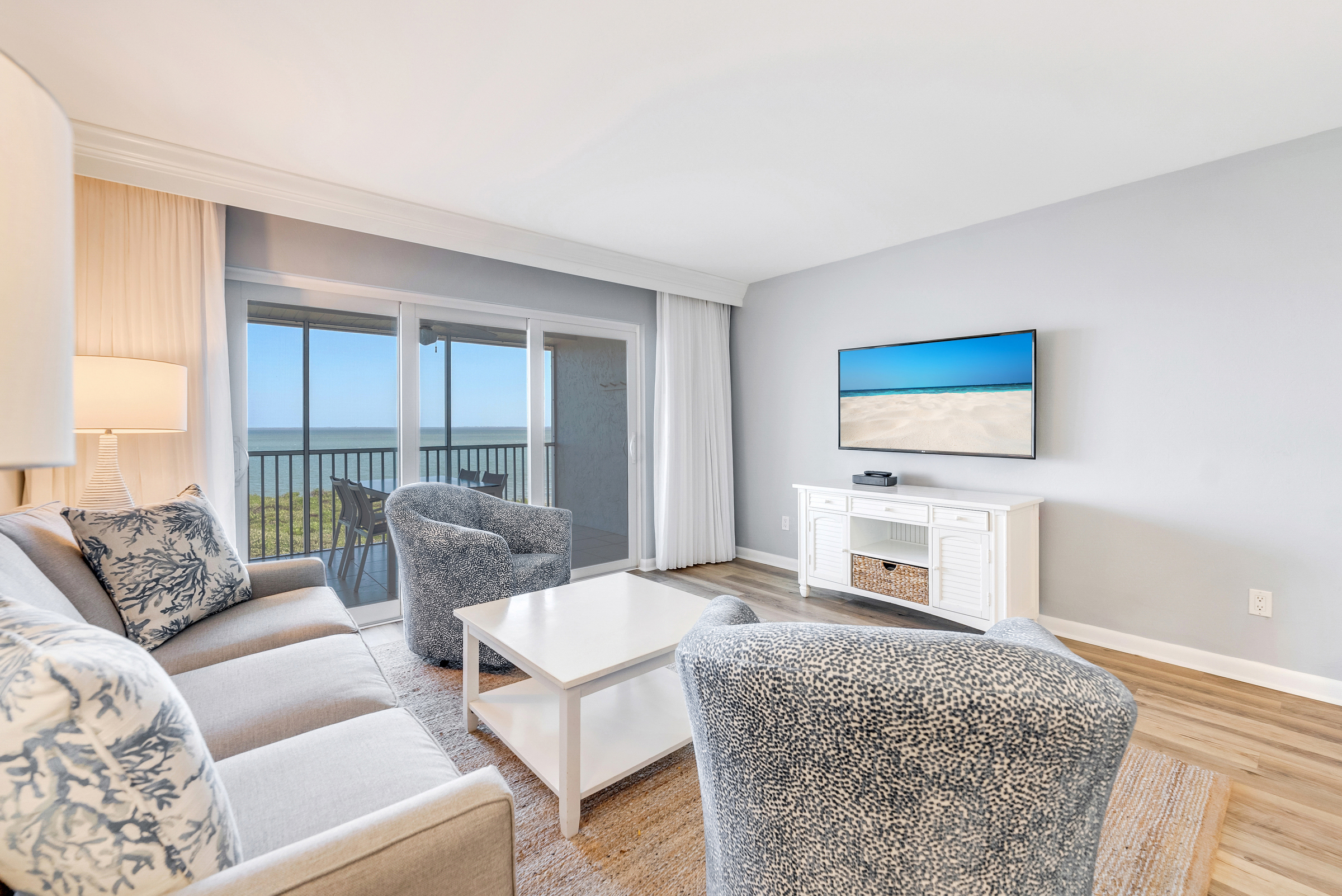Cozy living room with TV, comfy seating, and ocean view balcony