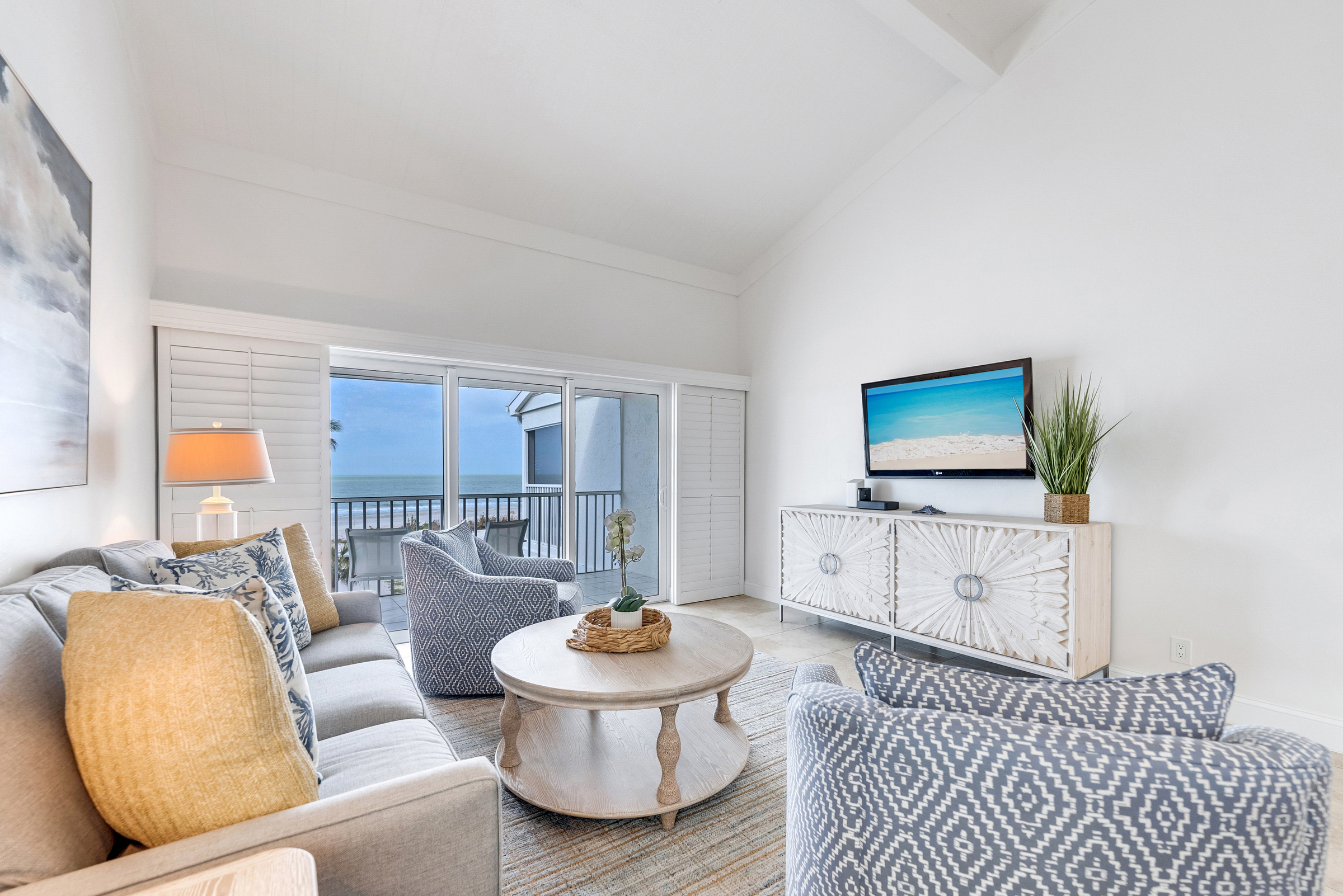 Sofa, chairs, coffee table, TV, and balcony view.