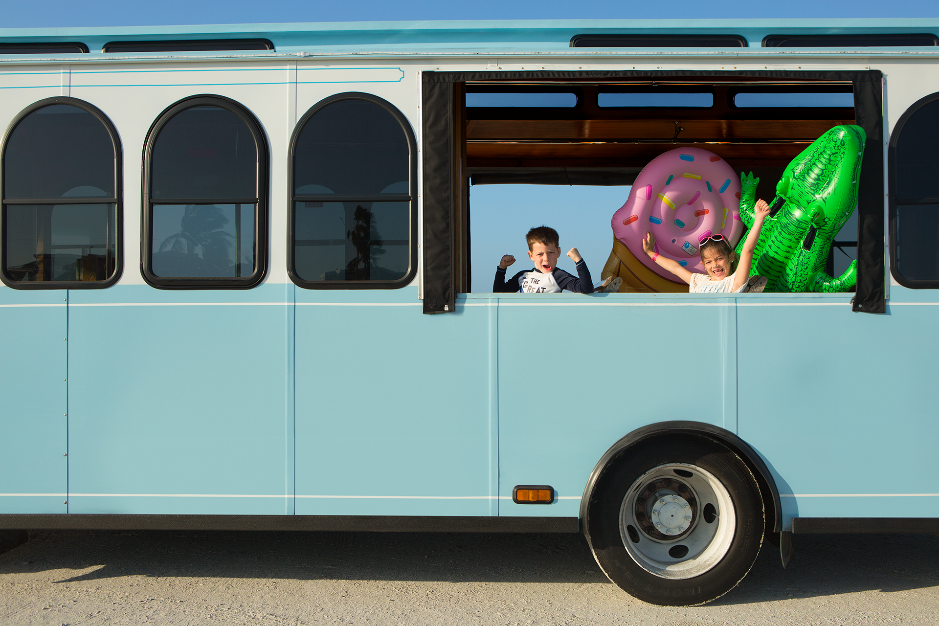 Kids smiling and waving from a beach trolley ride