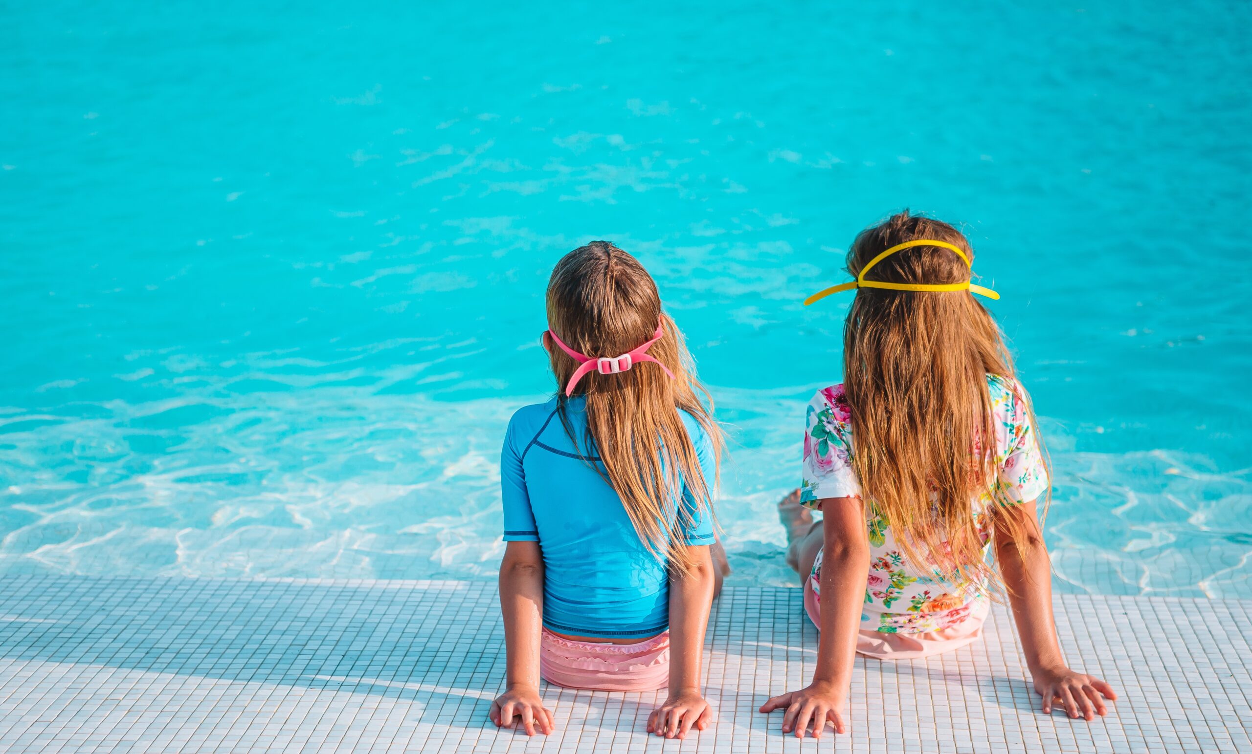 Adorable little girls playing in outdoor swimming pool on vacation