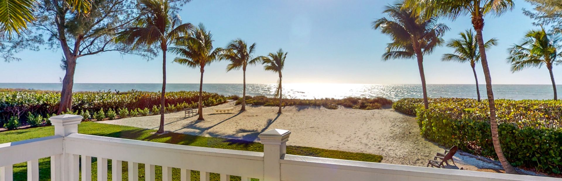 View from a porch looking out at the beach, palm trees, and ocean