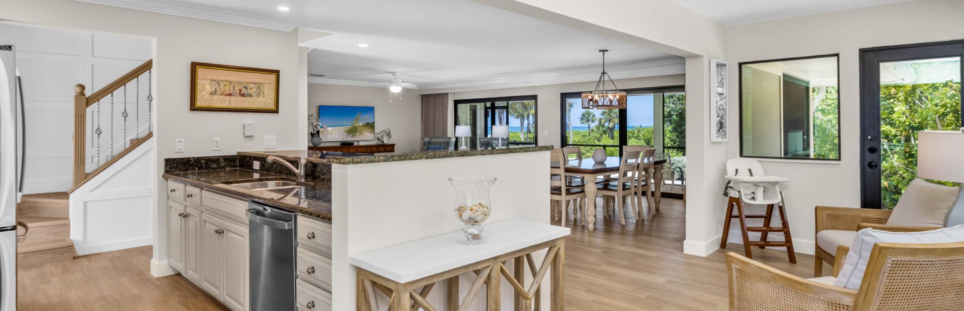 Kitchen with granite counters, dining area, and large windows overlooking greenery