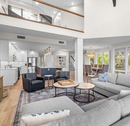 Living room with gray sectional, black chairs, and open kitchen and dining area