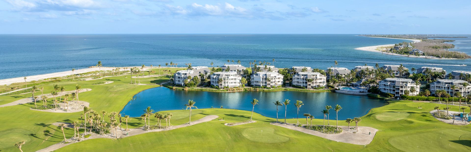 Aerial view of coastal condos and golf greens by the water.