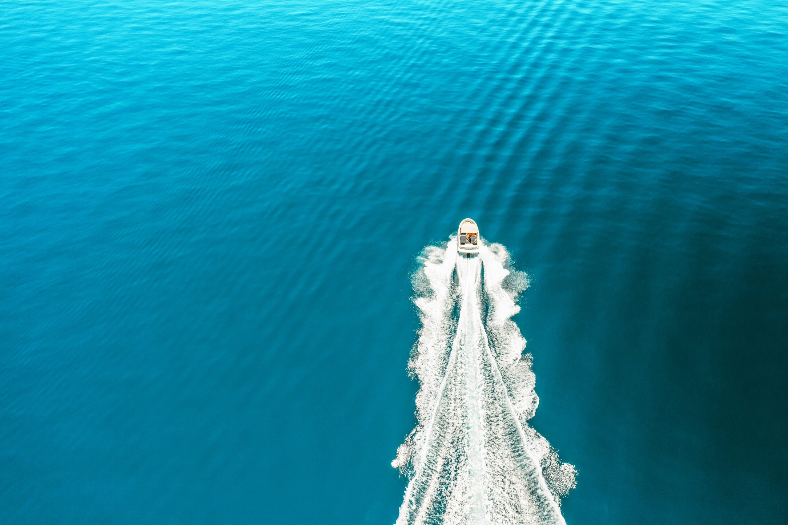 Aerial view of a boat speeding through blue water