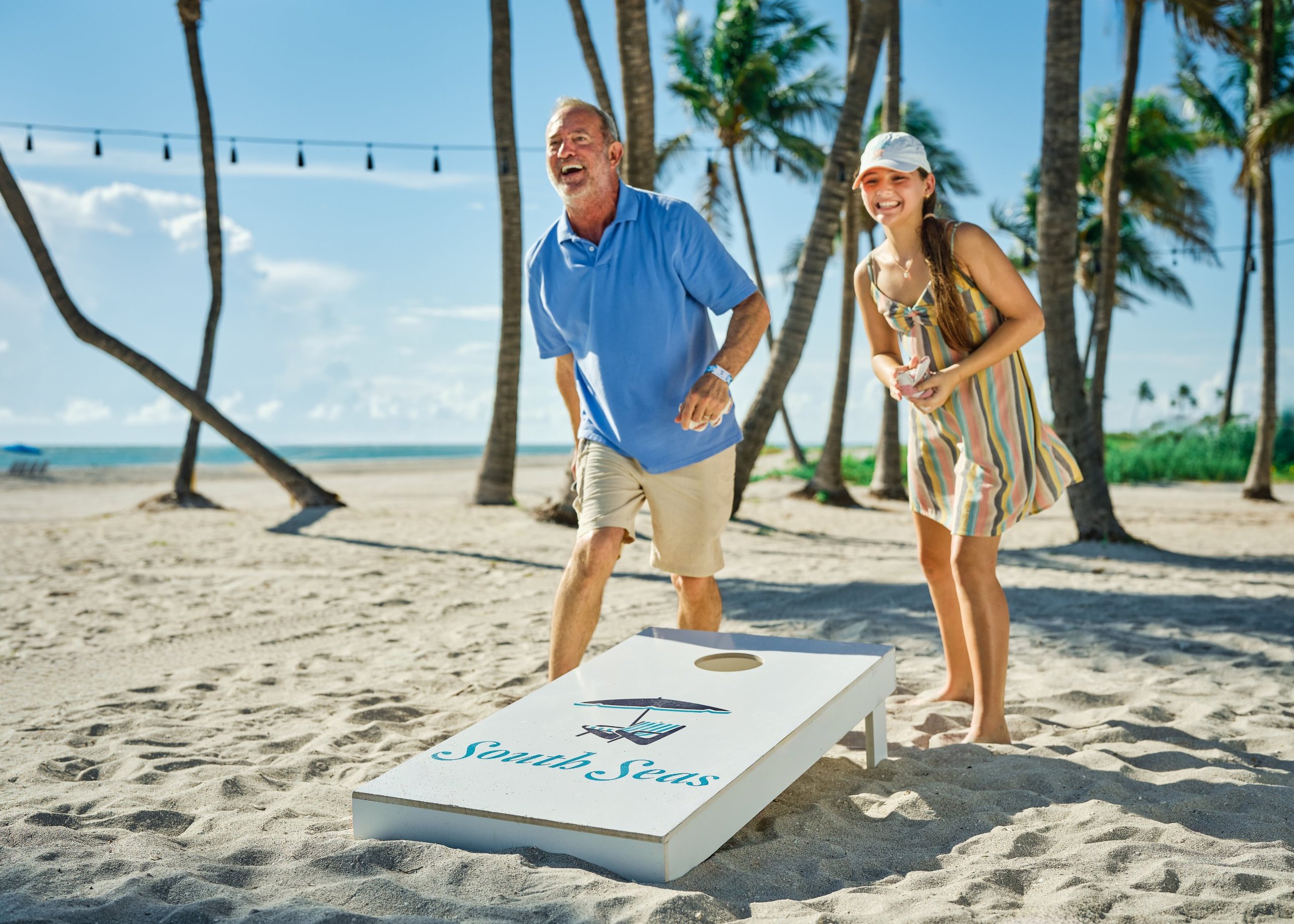 Guests playing cornhole on the beach at South Seas